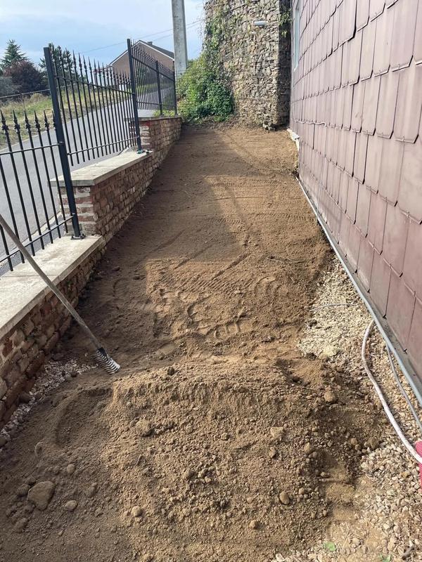 Bande de terre en cours de préparation le long d’une façade et d’une clôture